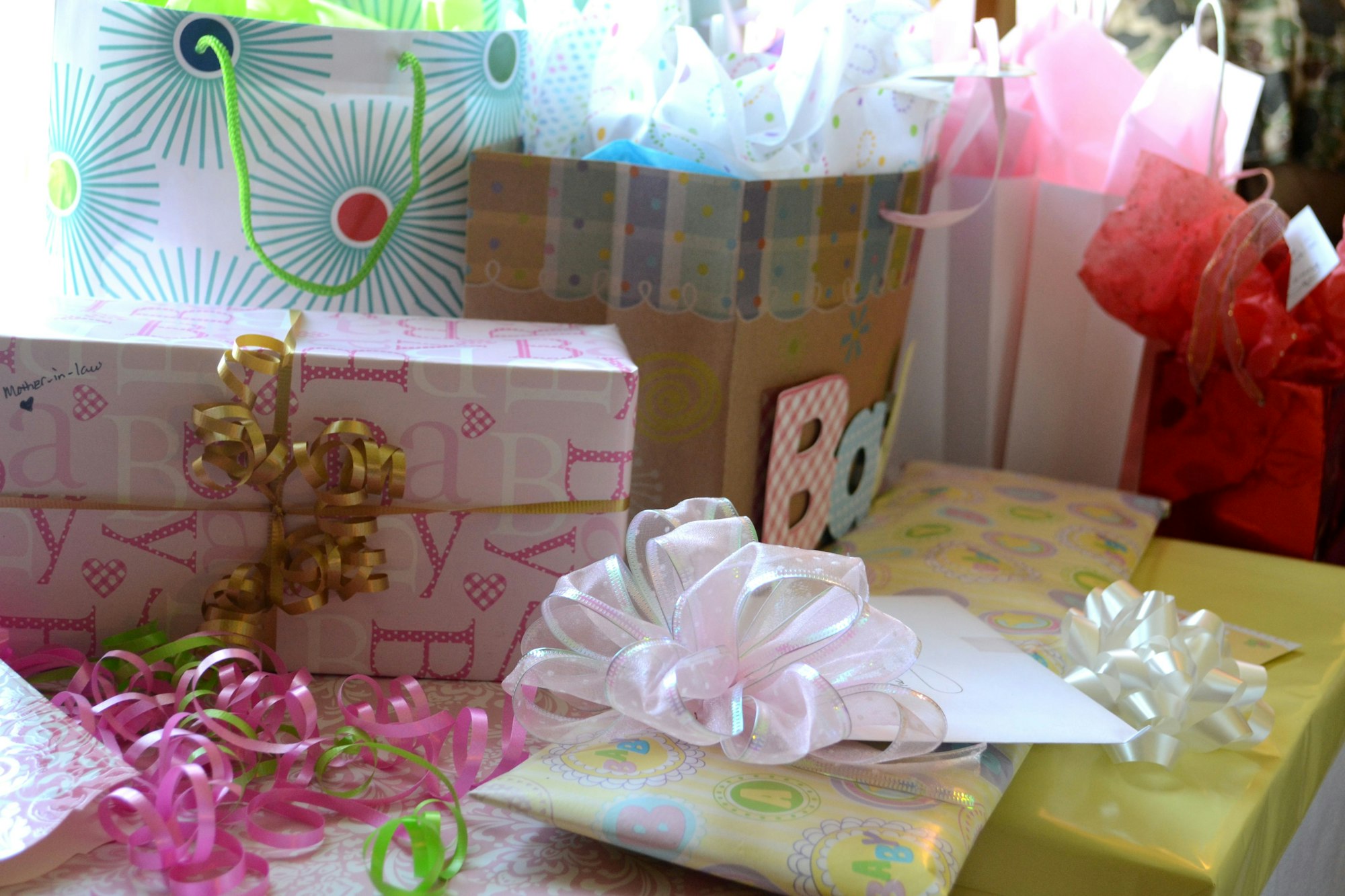 An assortment of baby gifts waiting to be opened at a baby shower for a little girl.